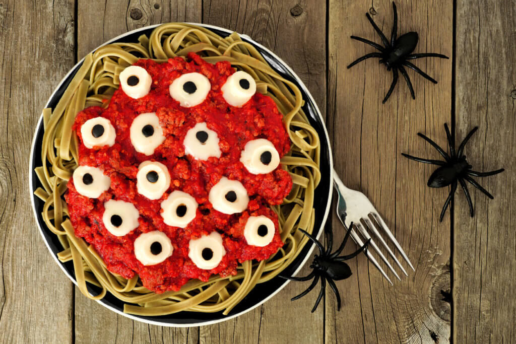 Halloween eyeball pasta, above view on old wood with spiders