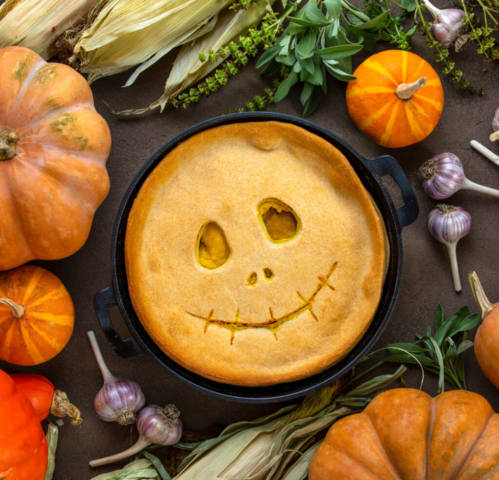 Halloween kids party pumpkin pie with a cute smiling face, top view