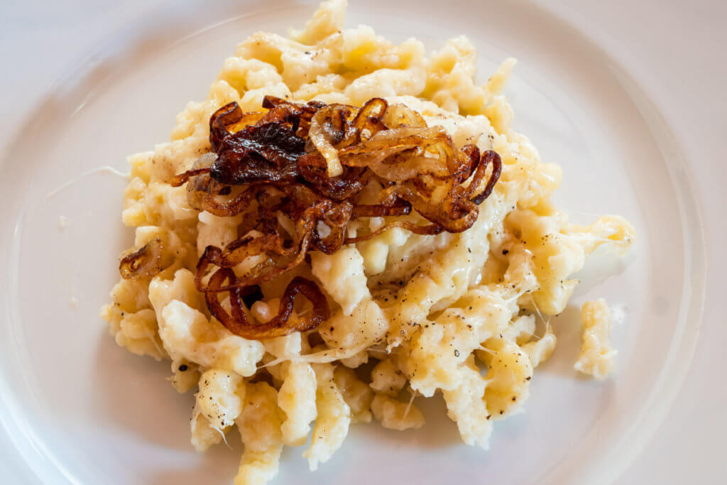 Tyrolean Chees Noodles or Pasta called Kaesespaetzle with Fried Onion on a White Plate, a Typical and Traditional Austrian Dish
