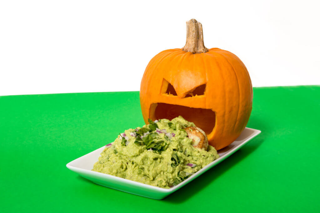 Carved pumpkin puking guacamole from the mouth.