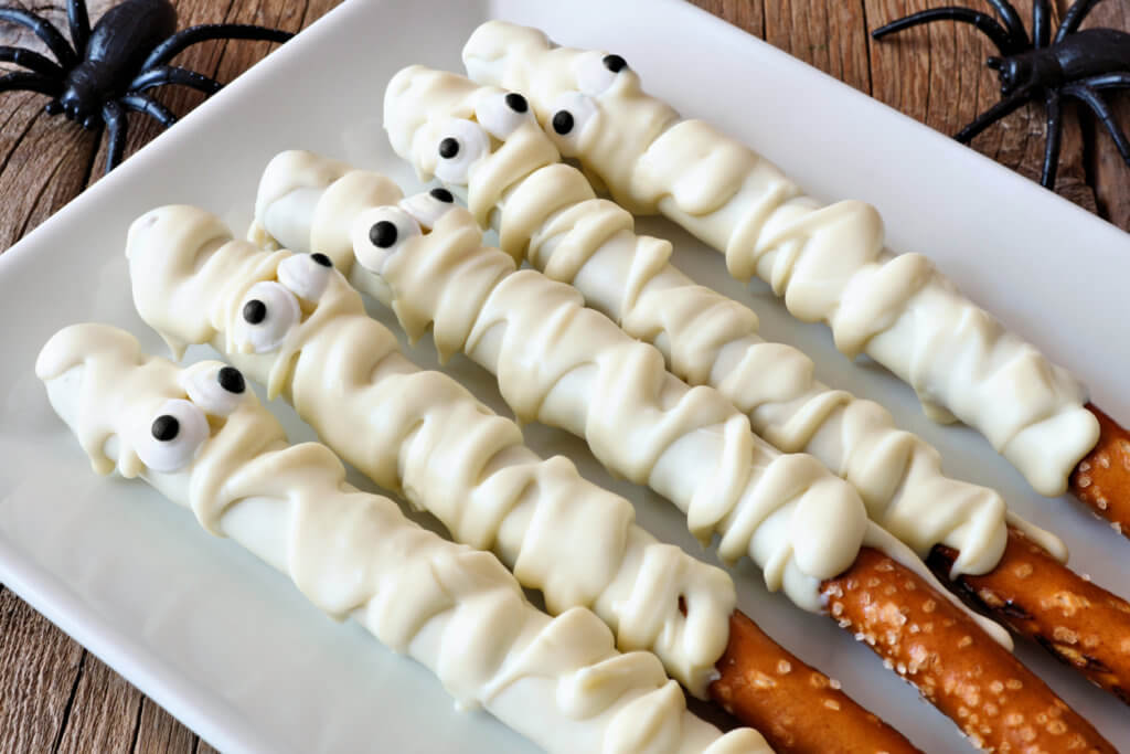 Spooky Halloween mummy, candy dipped pretzel rods, close up on plate