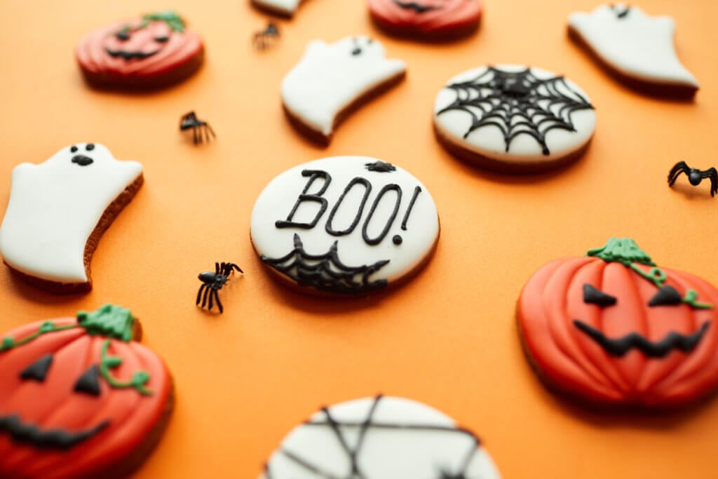 Close-up sweet sugar Halloween cookies with glaze, focus on Boo inscription written on cookie.
