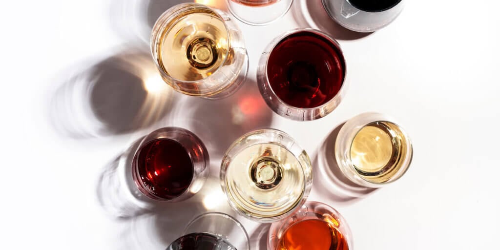 Red, rose and white wine in glasses on white background, top view. Wine bar, shop, winery, wine tasting concept. Hard light and harsh shadows (Red, rose and white wine in glasses on white background.