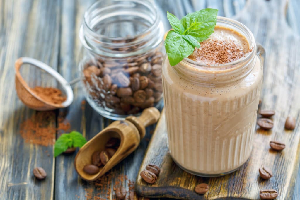 Coffee smoothie in a glass jar on the kitchen wooden table, selective focus.