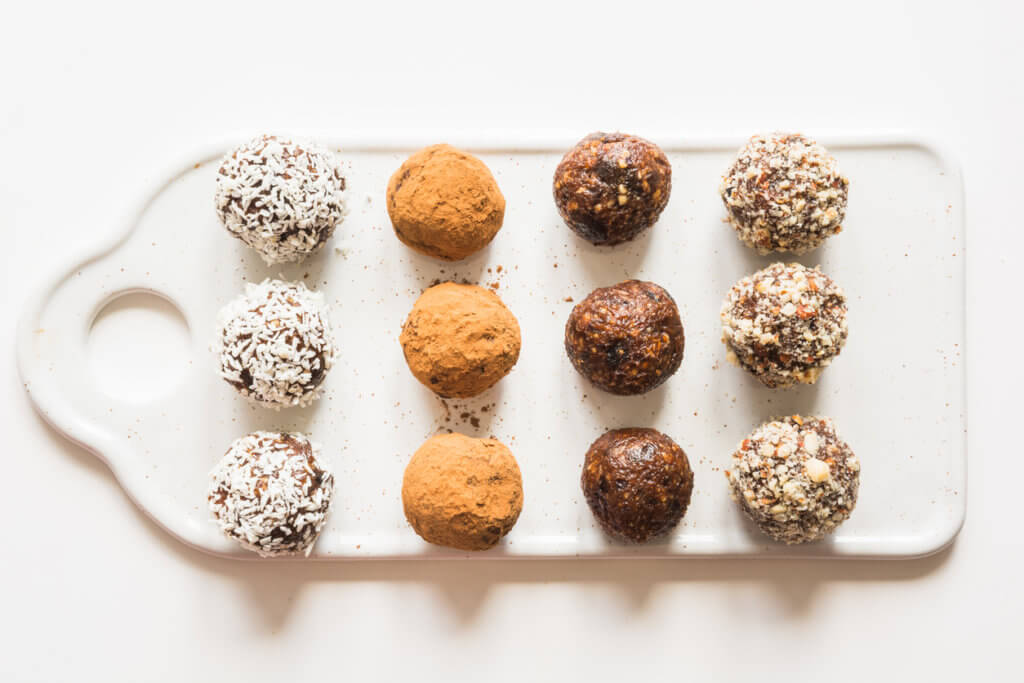 Homemade energy balls with cacao and nuts on white background. Healthy food for children, sweets substitute. Space for text.