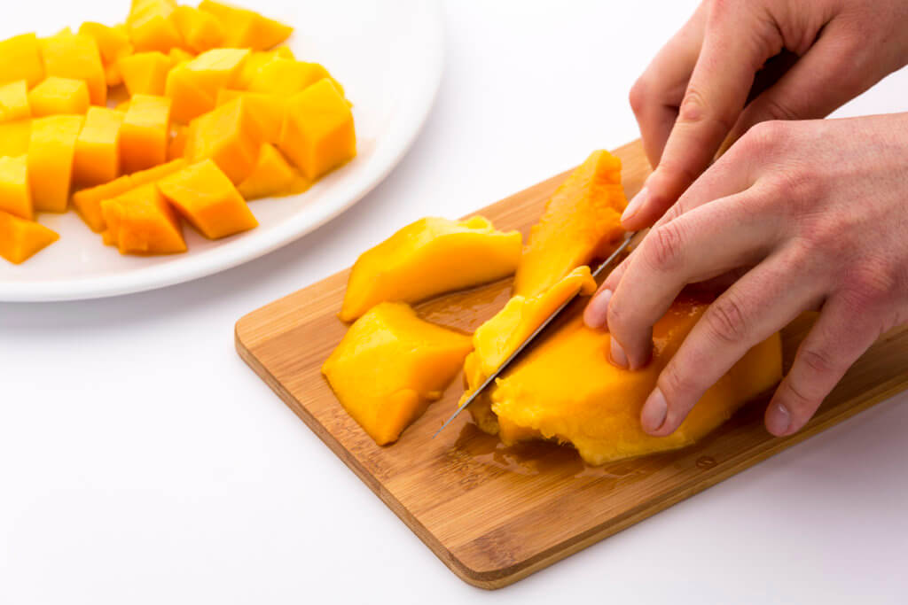 Separating mango fruit flesh from its oblong, flat pit. 