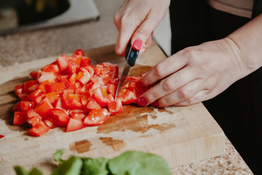 Woman hands cut red tomato