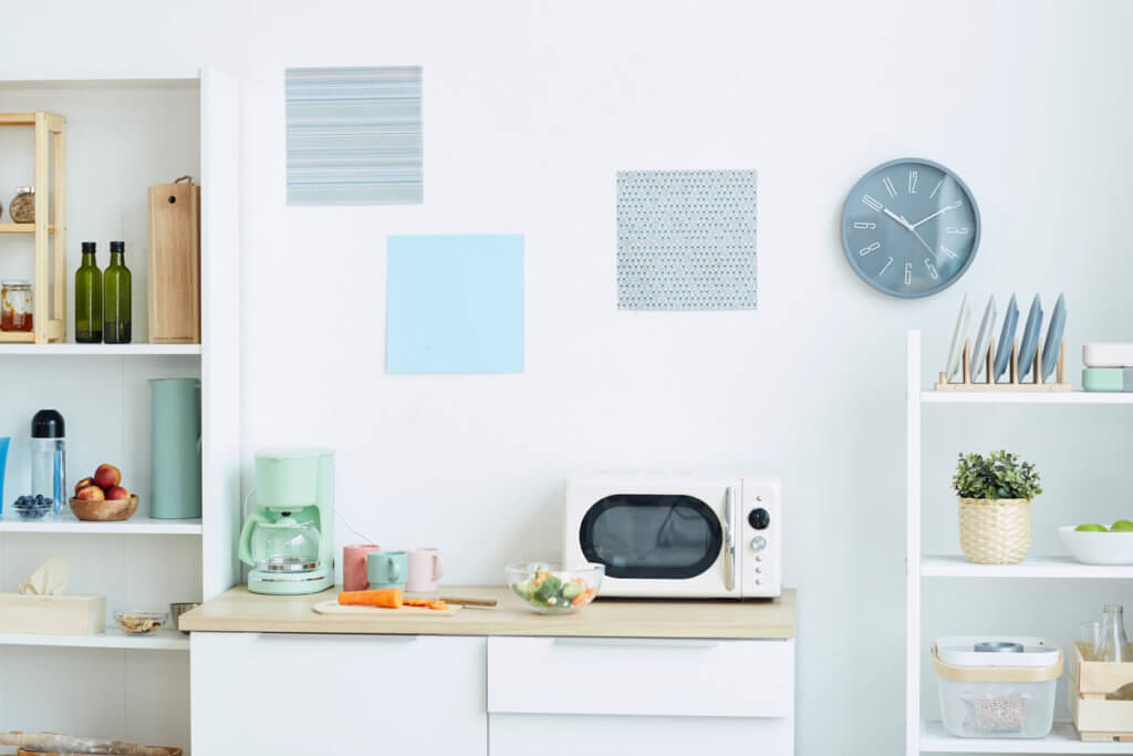Background image of contemporary kitchen interior in pastel colors with focus on microwave oven and analog clock, copy space