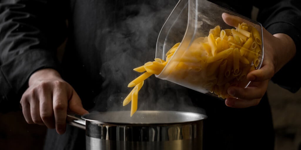 pouring pasta into boiling water.
