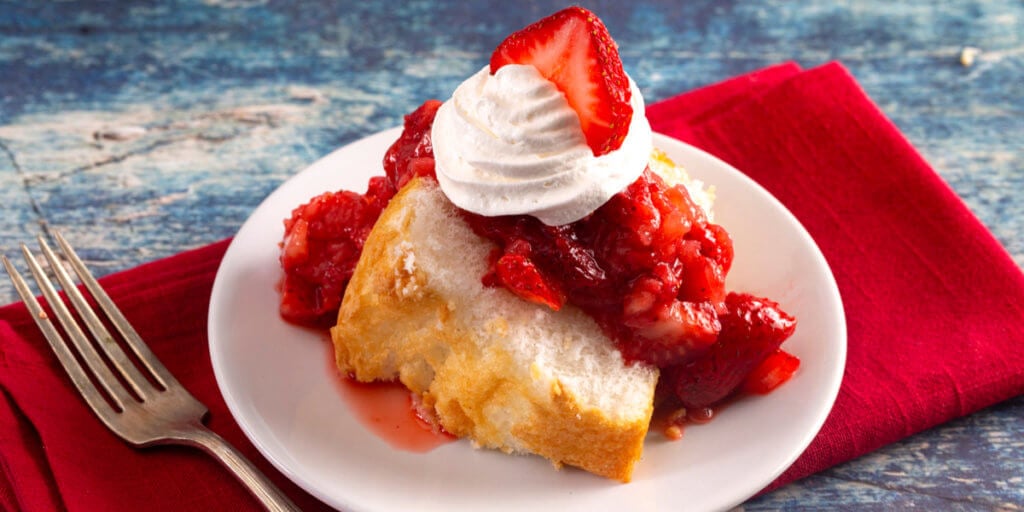 Slice of angel food cake with berries and cream.