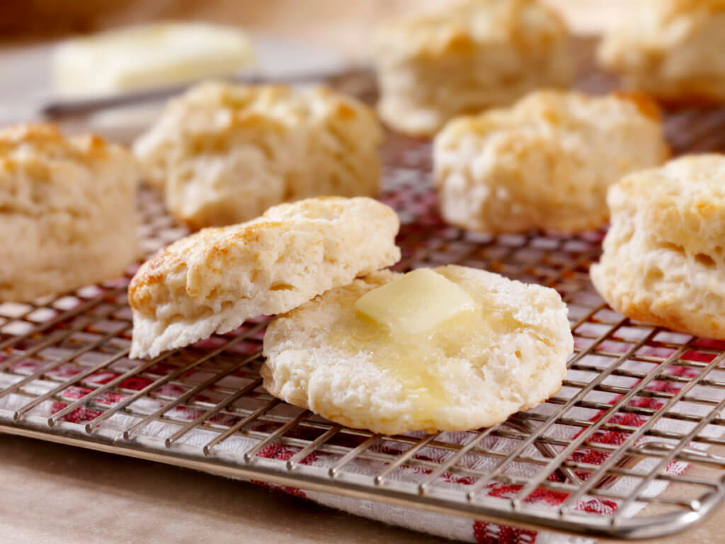 Homemade Buttermilk Biscuits Cooling on a rack in the Kitchen with Melting Butter.