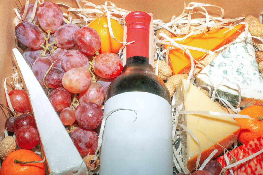 Cardboard gift box with red wine and fruit closeup. 
