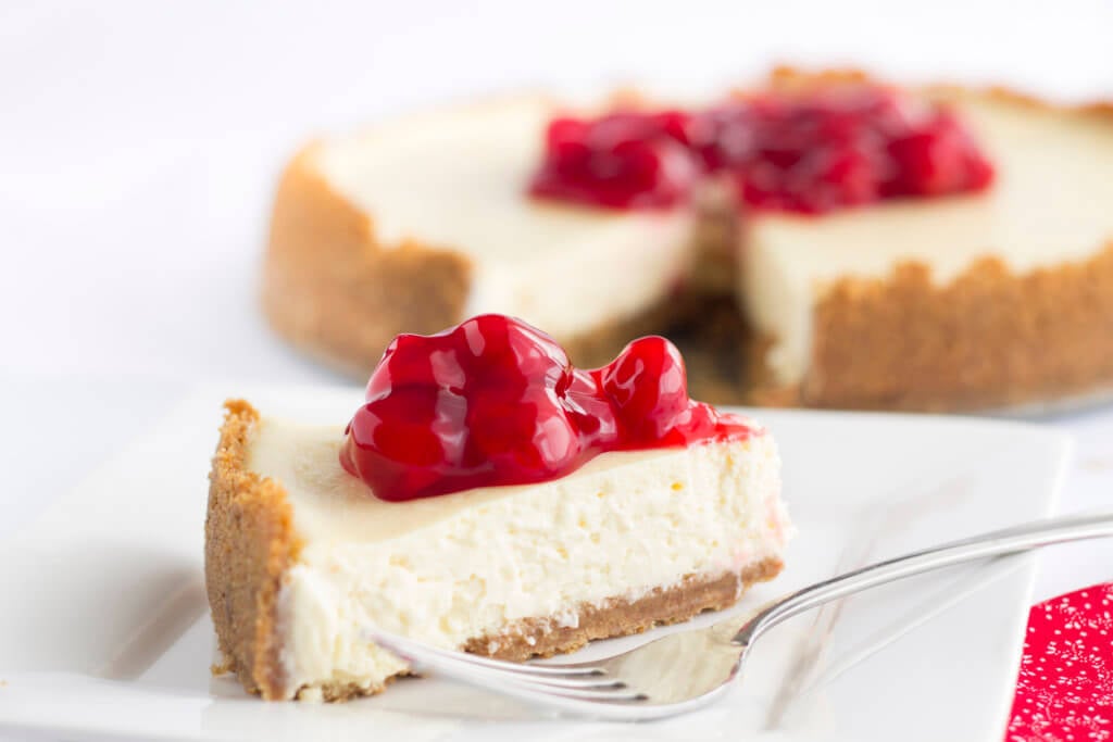 Delicious sweet red cherries top a smooth, creamy, decadent slice of cheesecake.