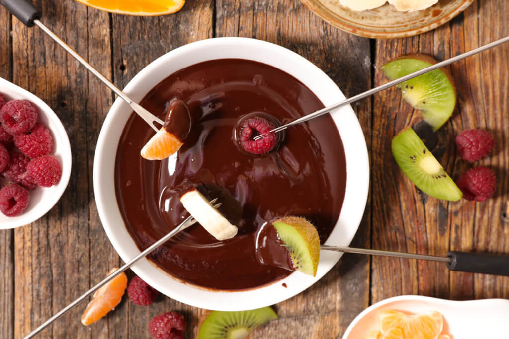 chocolate fondue with fruits being dipped in.