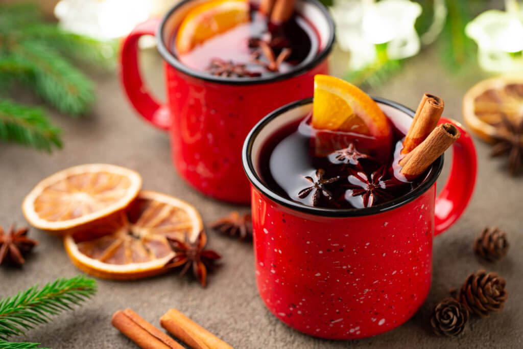 Two cups of christmas mulled wine or gluhwein with spices and orange slices on rustic table top view. Traditional drink on winter holiday.