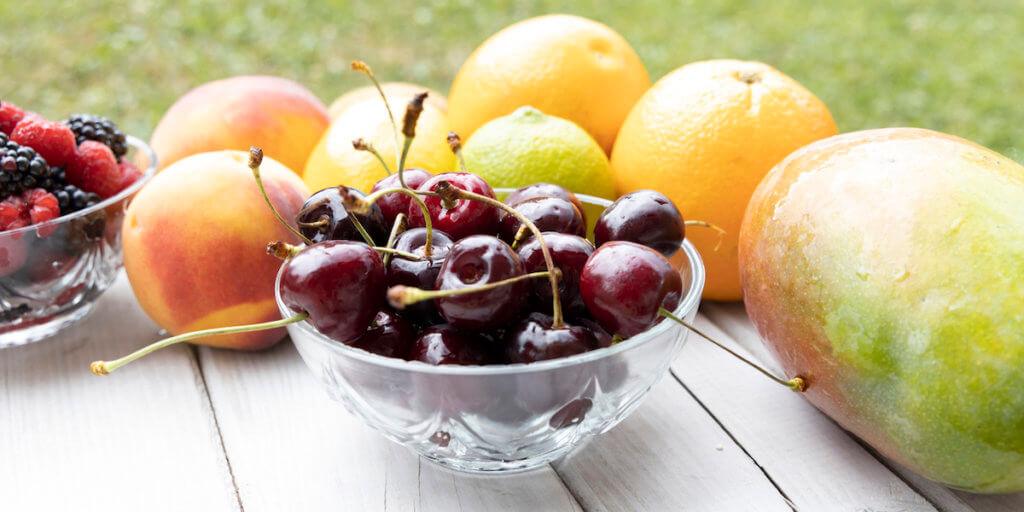 Fruits on a wooden table on a background of green grass