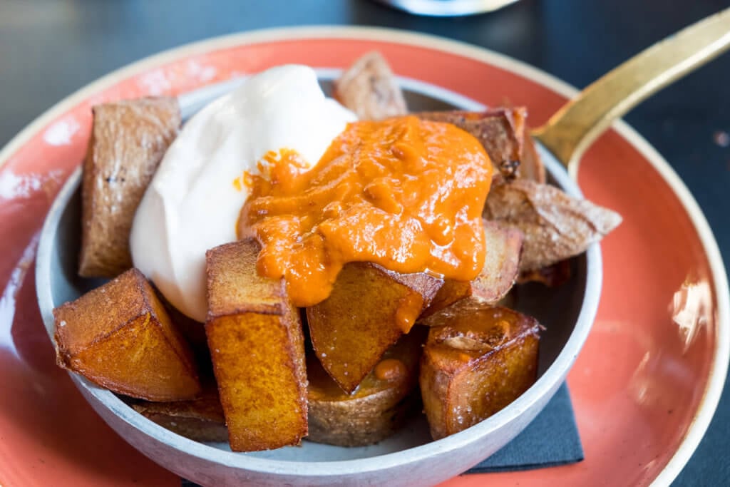 close up of inviting bowl of traditional spanish "patatas bravas", appetizer made with potatoes and paprika and garlic sauce.