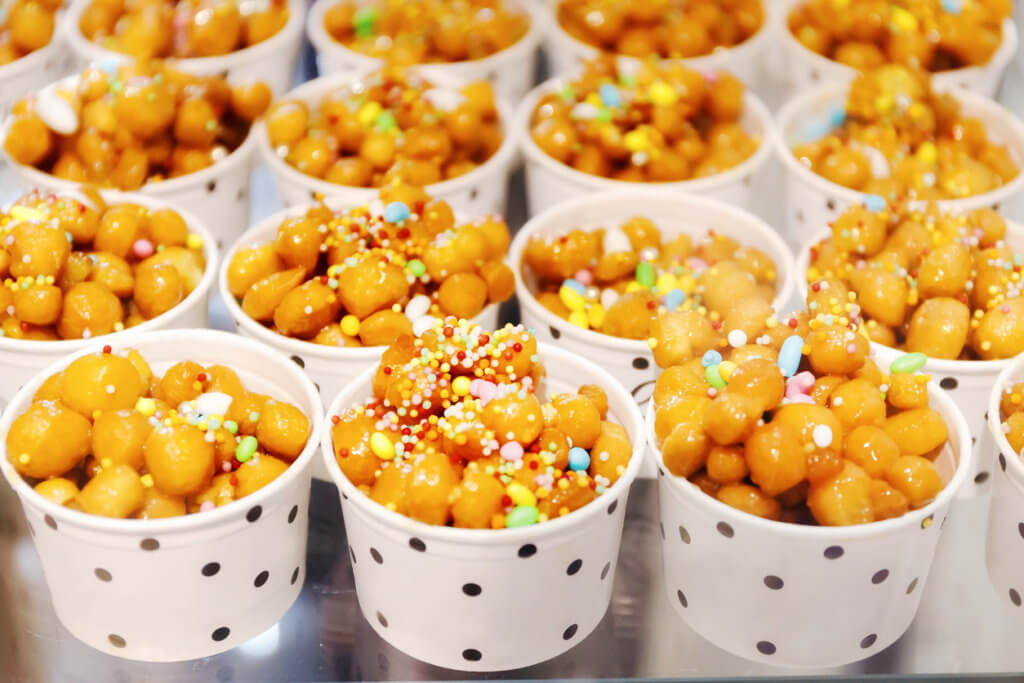 Cups filled with Struffoli, typical Neapolitan pastry consisting of many small balls of dough (realized on paper with flour, eggs, lard, sugar, anise liqueur), fried in oil and wrapped in warm honey. Decorated with colored sprinkles.
