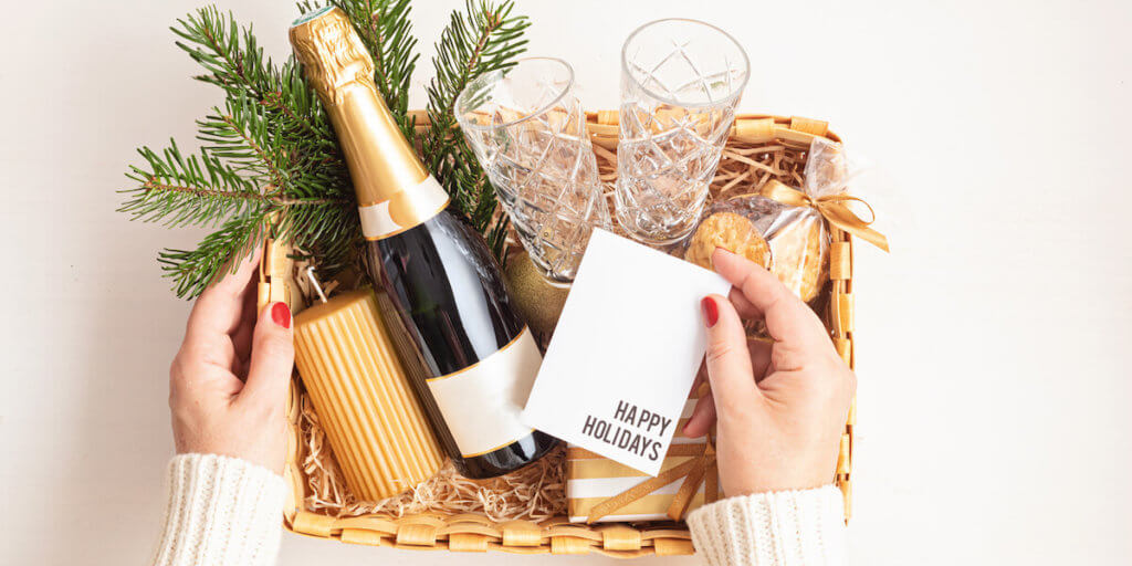 Refined Christmas gift basket for romantic holidays with bottle of champagne, wine glasses, cookies and candle