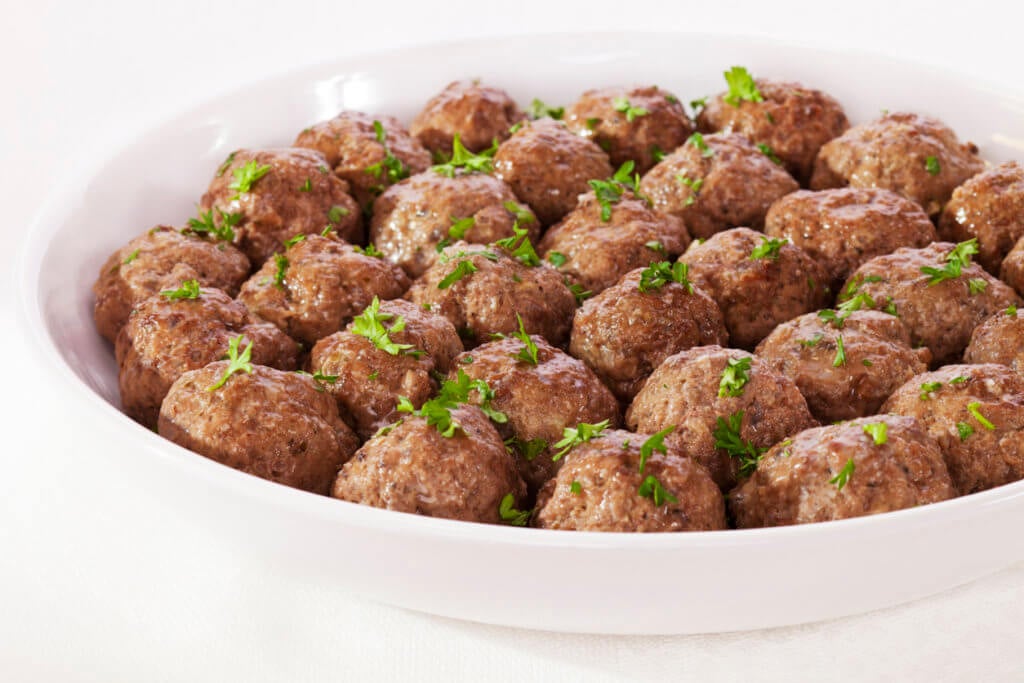 Meatballs in a serving dish with parsley.