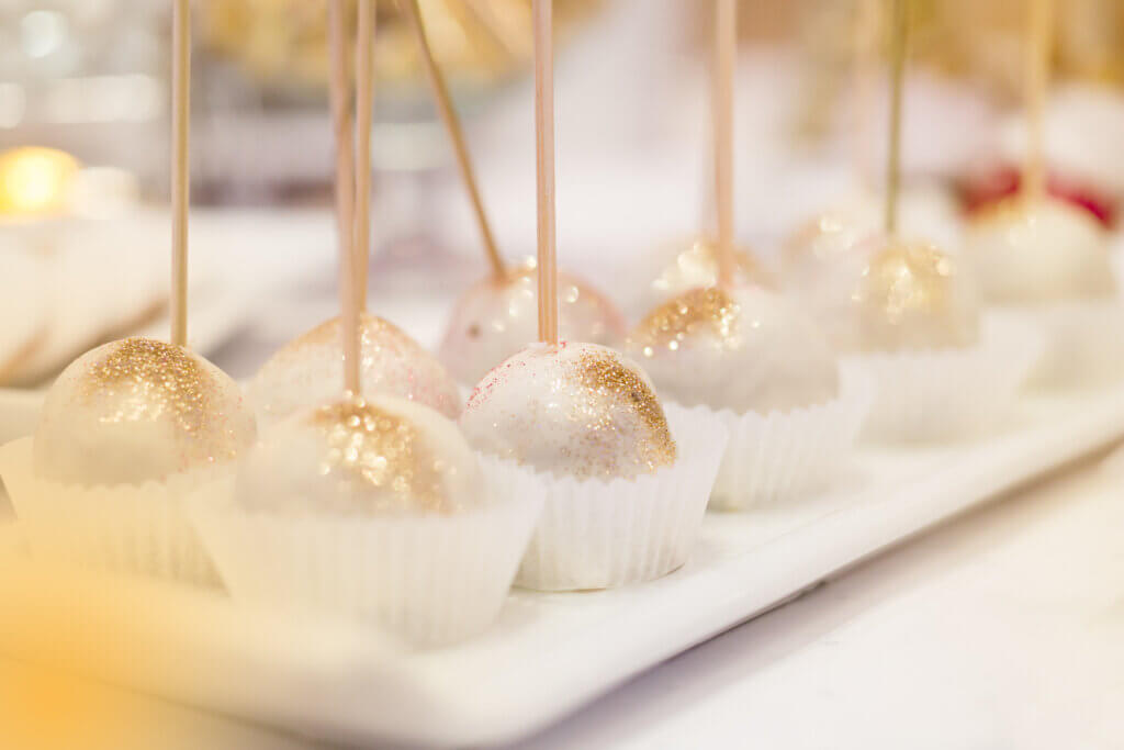 Cake pops coated completely in gold edible glitter, close up.