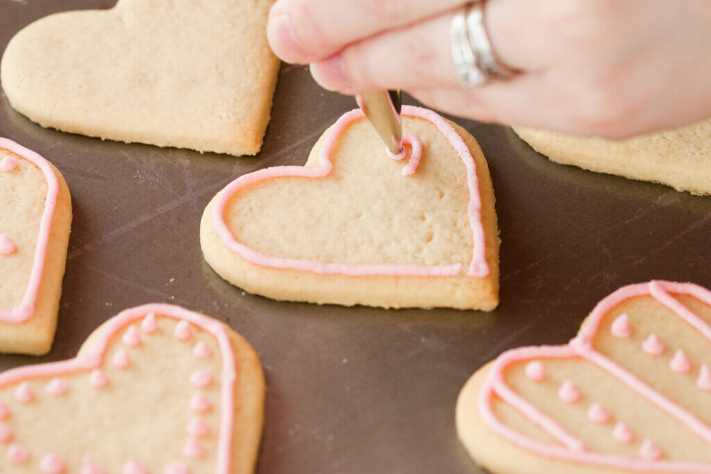 Woman's hand decorating Valentine's Day cookies.
