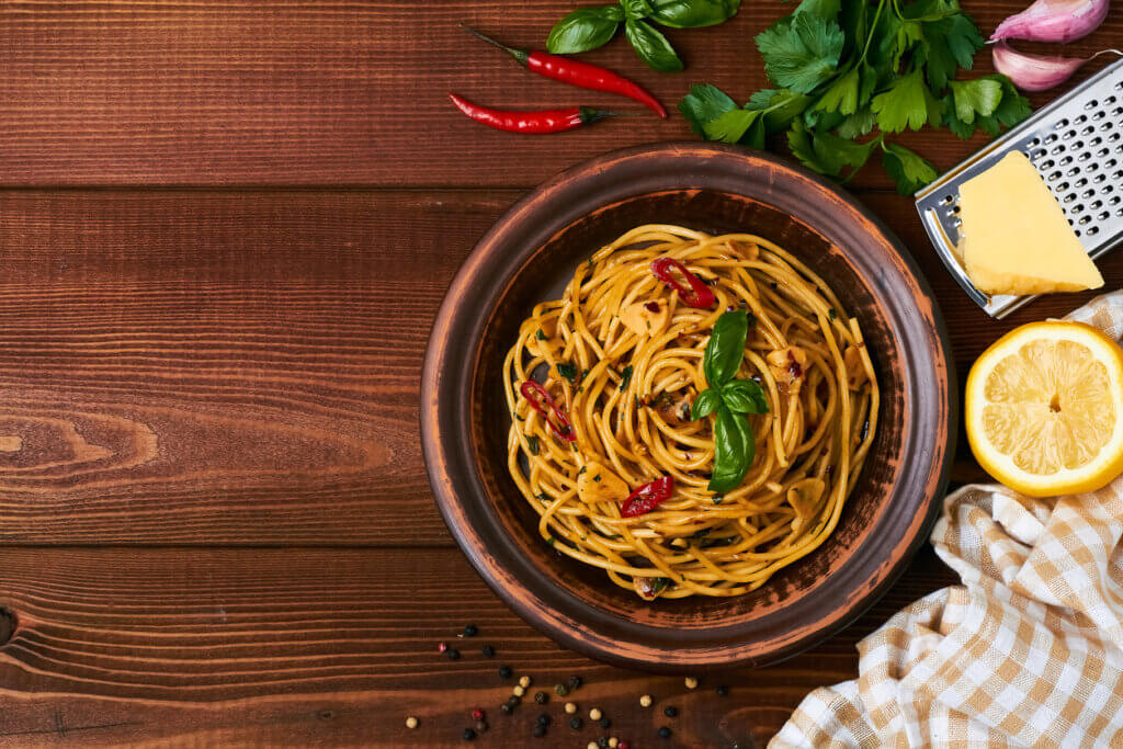 spaghetti pasta aglio e olio with chili flakes parsley garlic on brown background