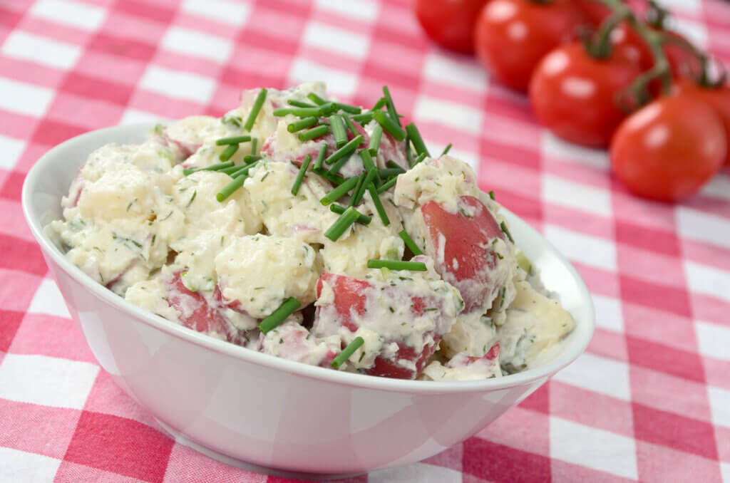 A freshly prepared potato salad made with red potatoes, mayonnaise, and fresh herbs.