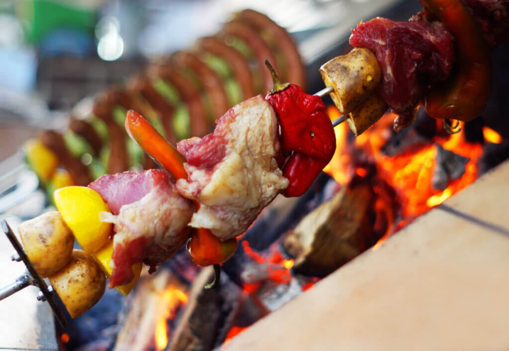 Meat and vegetable skewer on barbecue grill with fire.