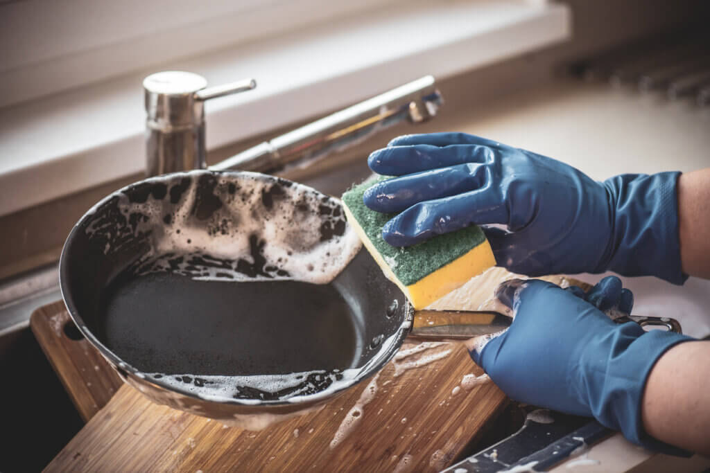 Hands in gloves wash dishes with detergents