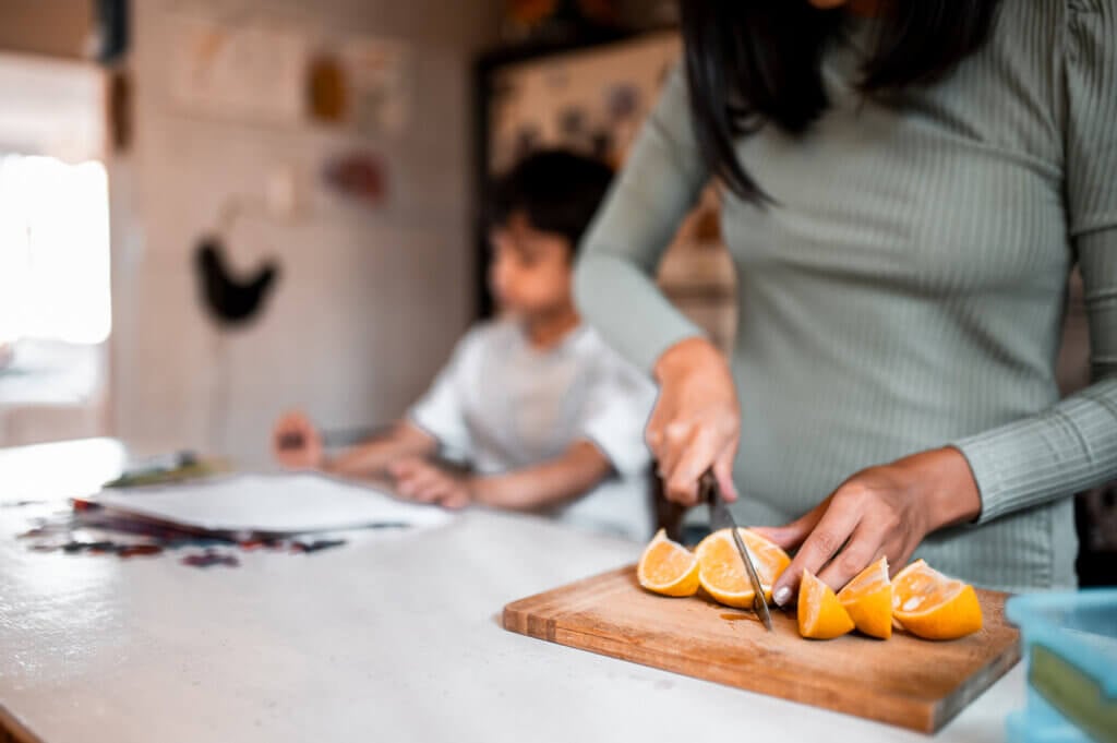 Mother cutting orange on slices