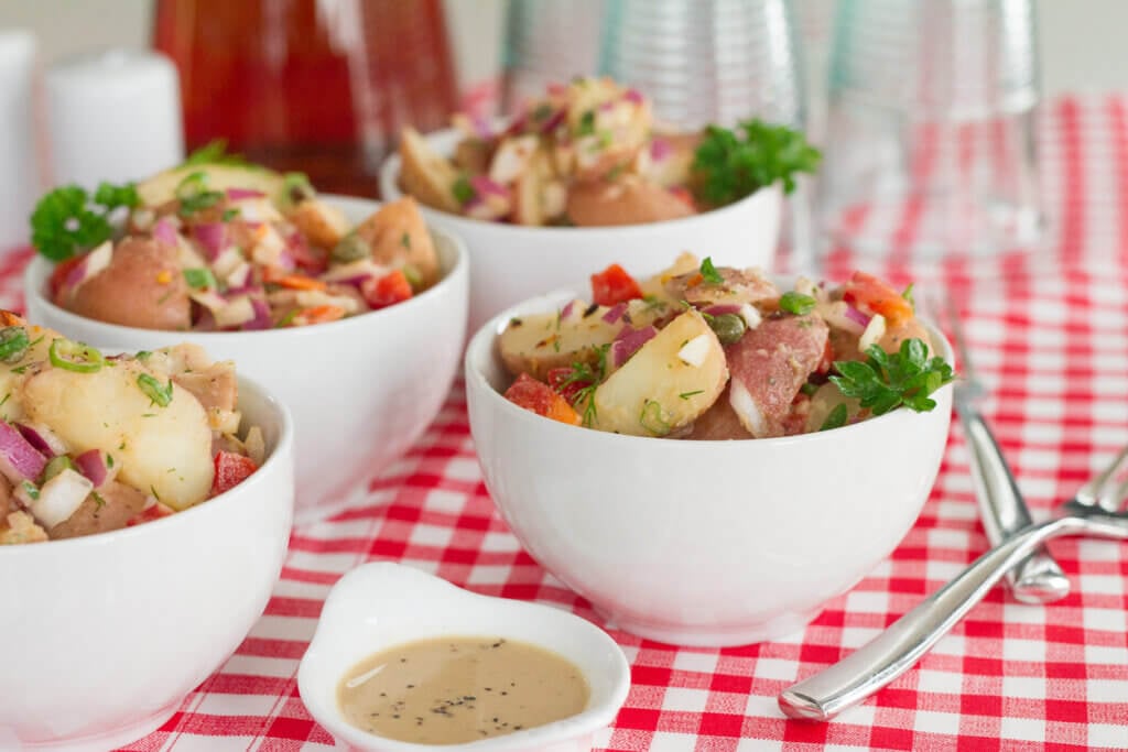 A healthier option to traditional potato salad made with quartered red potatoes, dill, scallions, onions, capers, red pepper flakes, red bell pepper, red onion, Dijon mustard, honey, champagne vinegar, olive oil, garlic, parsley, salt & black pepper.