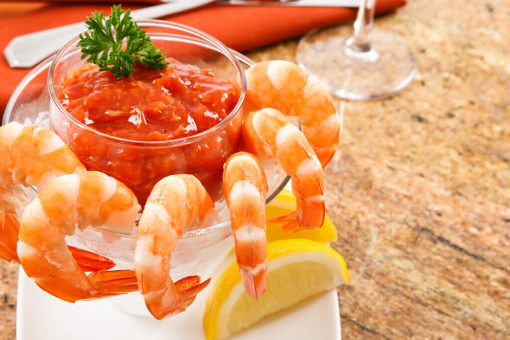 Cooked shrimp with cocktail sauce against a granite tabletop.  