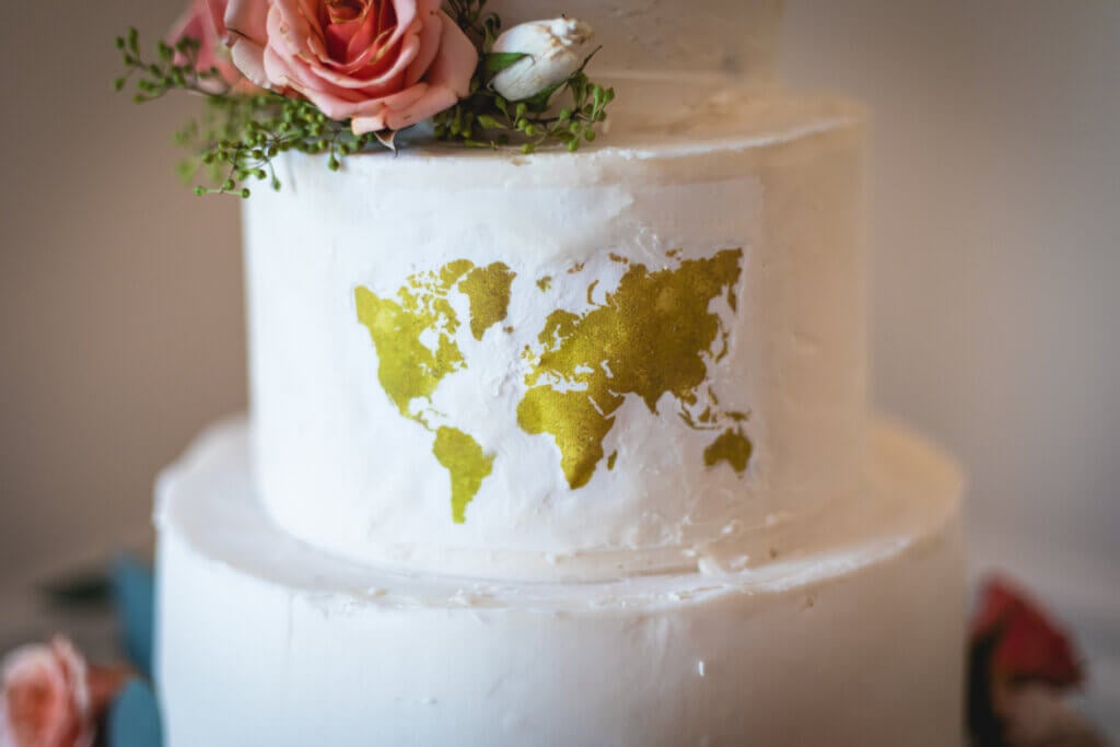 Gorgeous custom travel themed wedding cake with edible world map, pink roses, and message