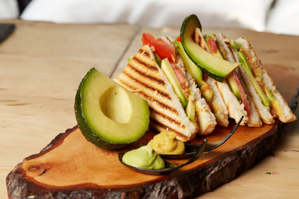 Vegan Club Sandwich with avocado on wooden tray