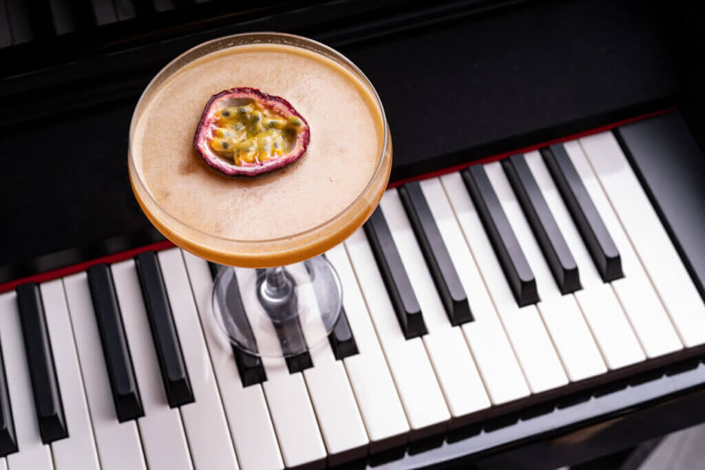 Passionfruit cocktail garnished with half of a passionfruit on a piano keyboard