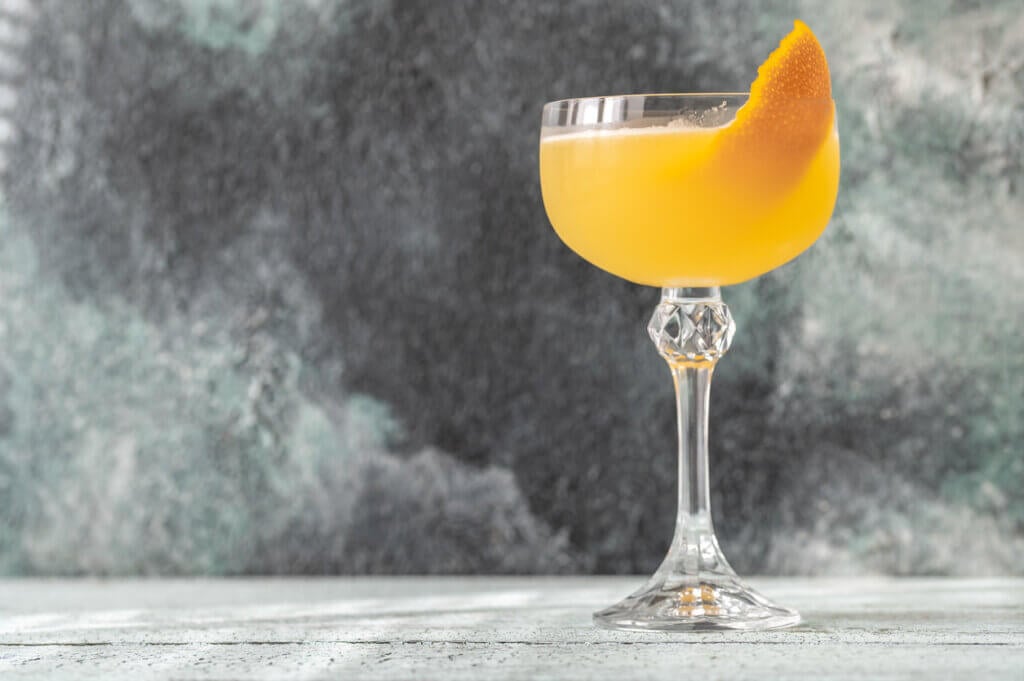 Glass of Bee's Knees cocktail garnished with orange zest