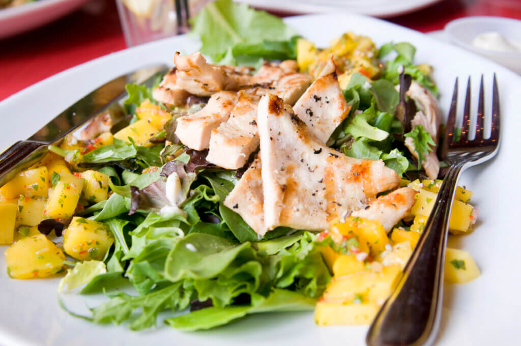 A fancy bed of greens topped with grilled local chicken and mangoes with a light herb-ed dressing.