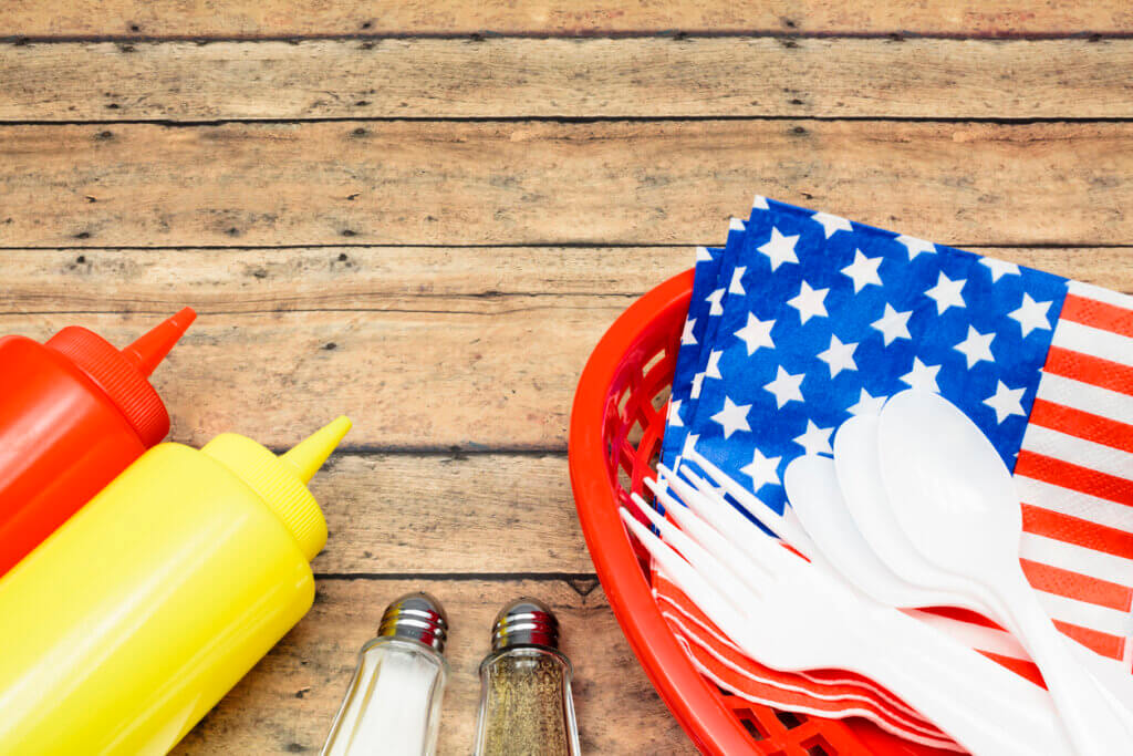 "Picnic table with condiments, utensils and flag napkin"