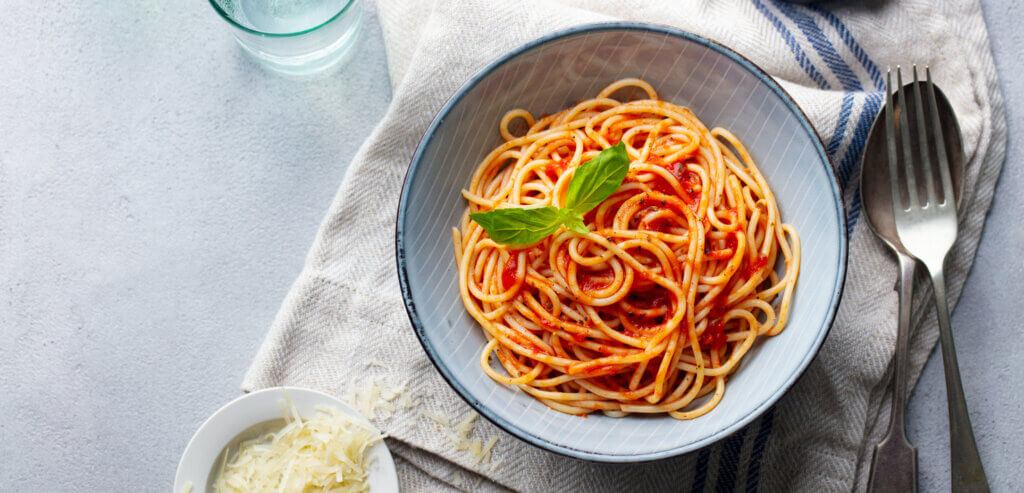 Pasta, spaghetti with tomato sauce and fresh basil in a bowl.