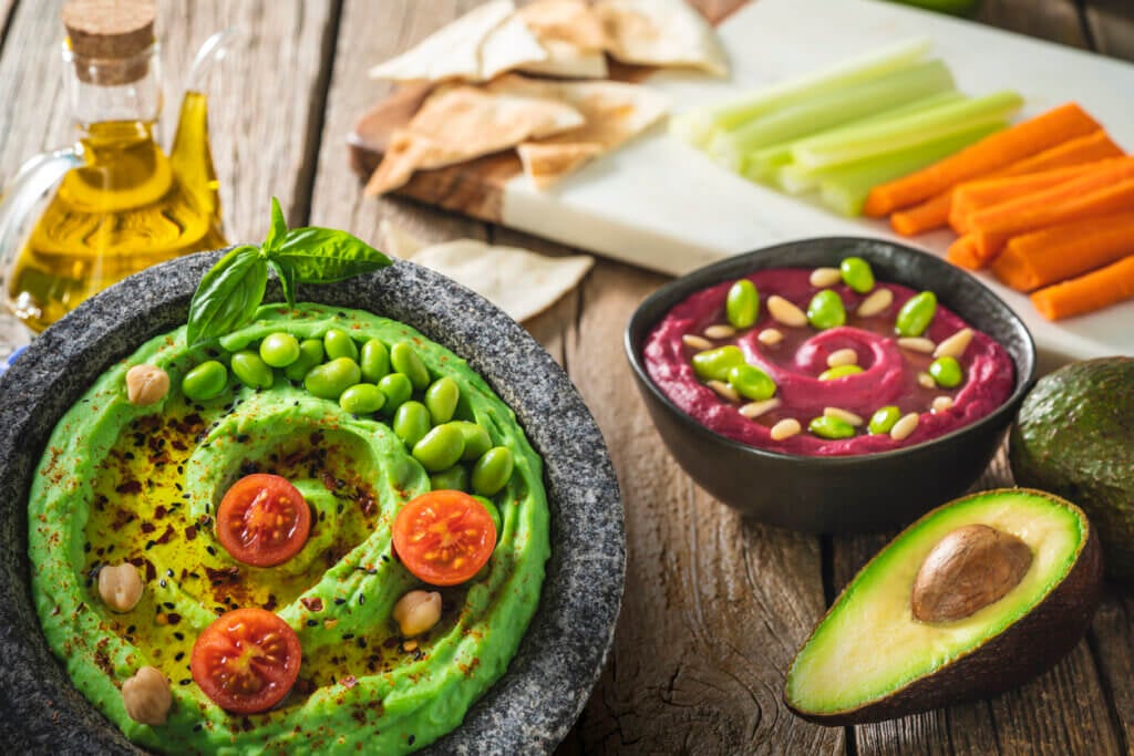 Avocado and edamame hummus recipe with olive oil and ingredients as a healthy Mediterranean diet with summer flowers and olive oil.