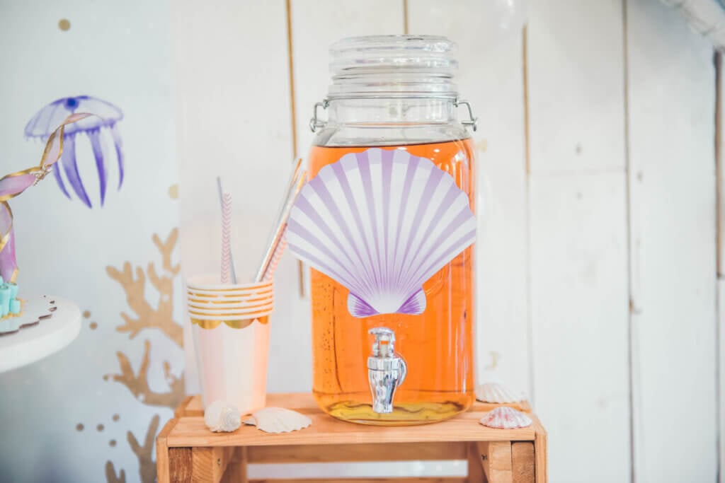 Lemonade in glass jar with tap on wooden stand indoor. Mermaid Candy Bar.
