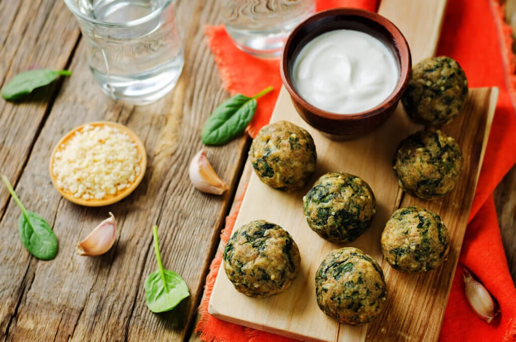 Cheese spinach balls with spinach leaves and greek yogurt sauce