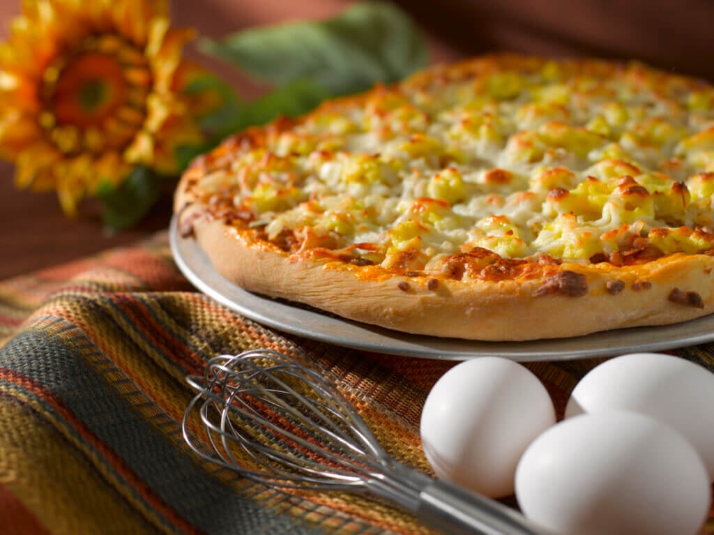 Breakfast pizza on a counter with eggs.
