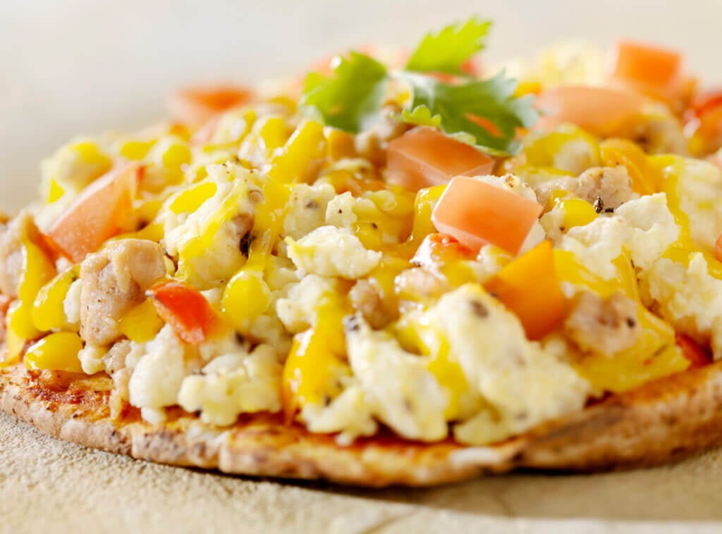"Breakfast Pizza on Pita Bread with Sausage, Scrambled Eggs,Tomatoes and Peppers.