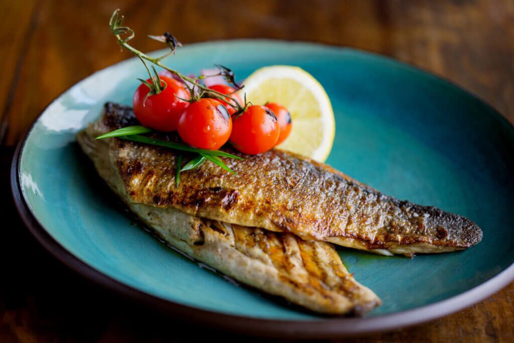 Freshly grilled trout, garnished with cherry tomato and lemon slices