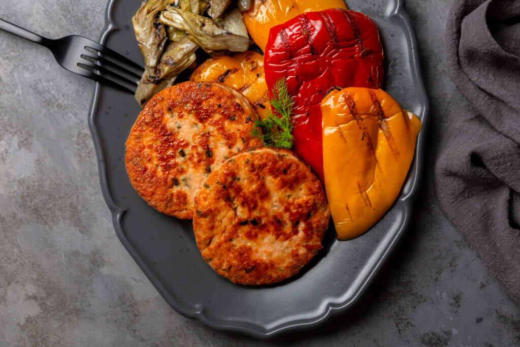 seafood cakes with grilled vegetables, bell peppers and artichoke.