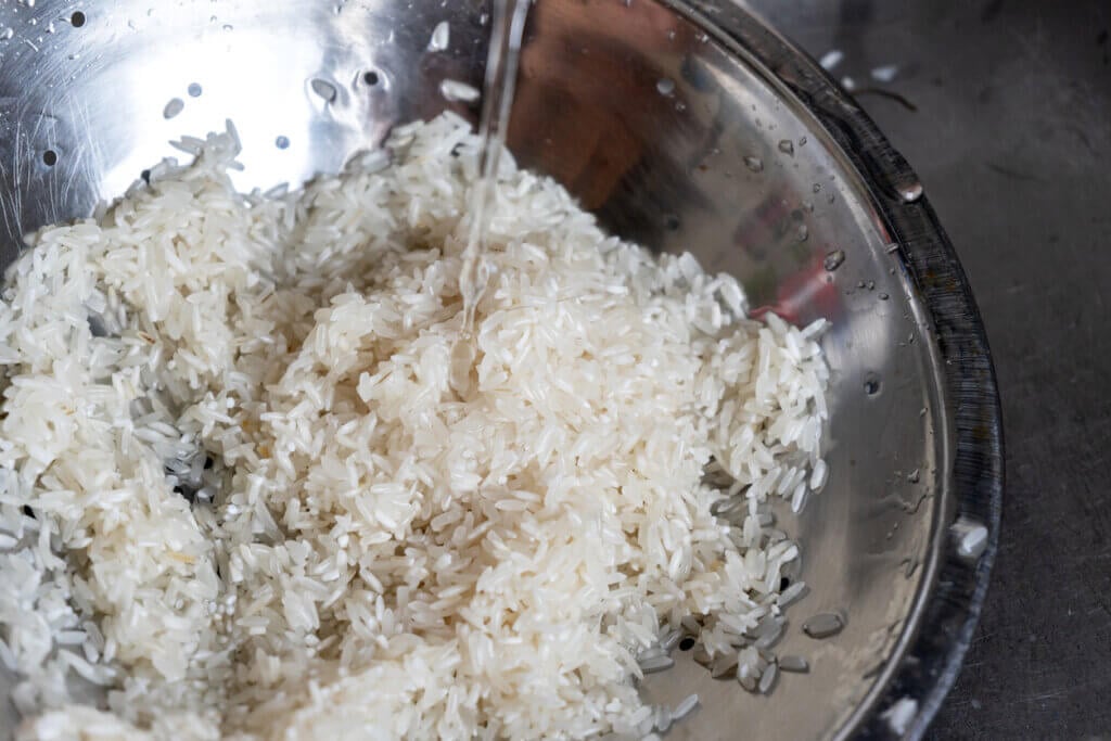 Washing white rice in metallic bowl