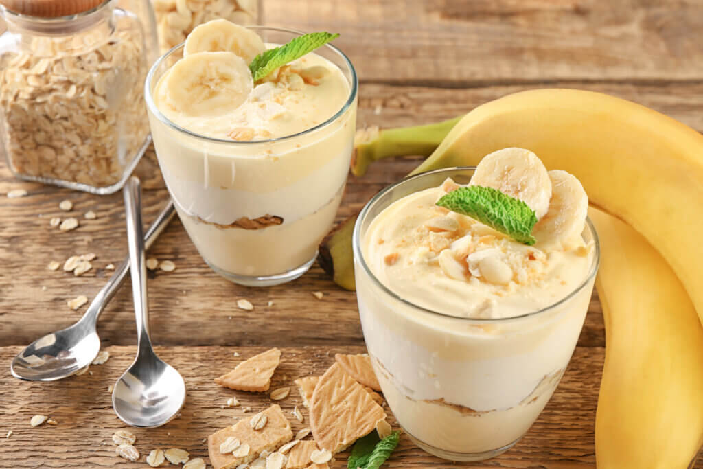 Glasses with delicious banana pudding on table