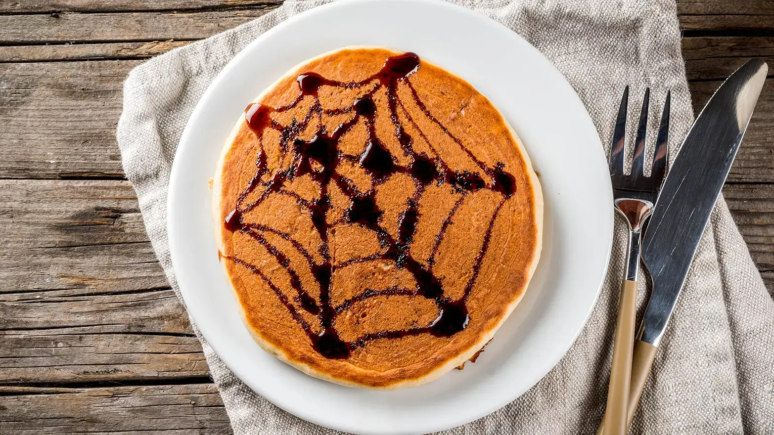 Pancake with spider web drawn in red syrup 